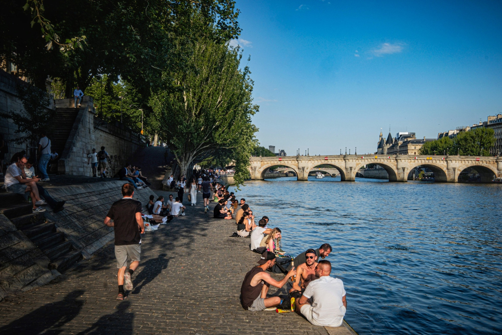 Des Parisiens profitent de la fraîcheur des quais de Seine, au pied du Pont Neuf, à Paris. © Marc Barrot Aujourd'hui en Europe - 23 juin 2026