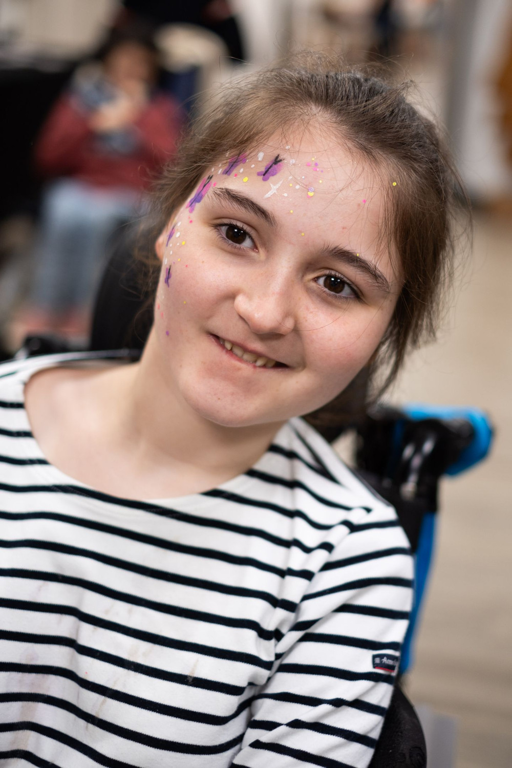 Zoé sourit dans son fauteuil avec un maquillage