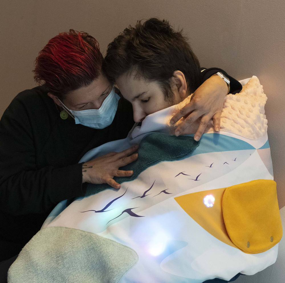 Une personne est enroulée dans le plaid et accompagné d'une aidante