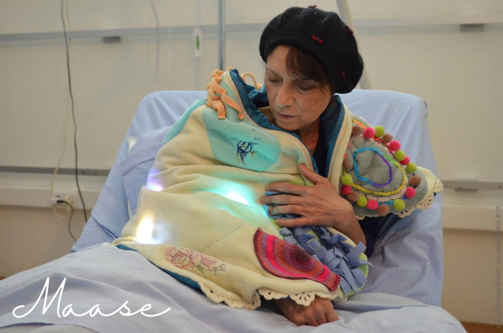 Personne dans un lit d'hôpital enveloppée dans un plaid lumineux sur les épaules